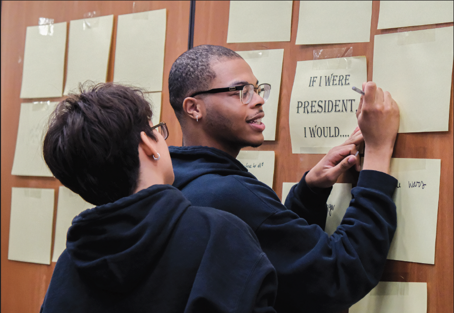 TCC student Kornelius Washington joins other attendees in writing the policies they would implement if they were elected president in a student-created display during the watch party.